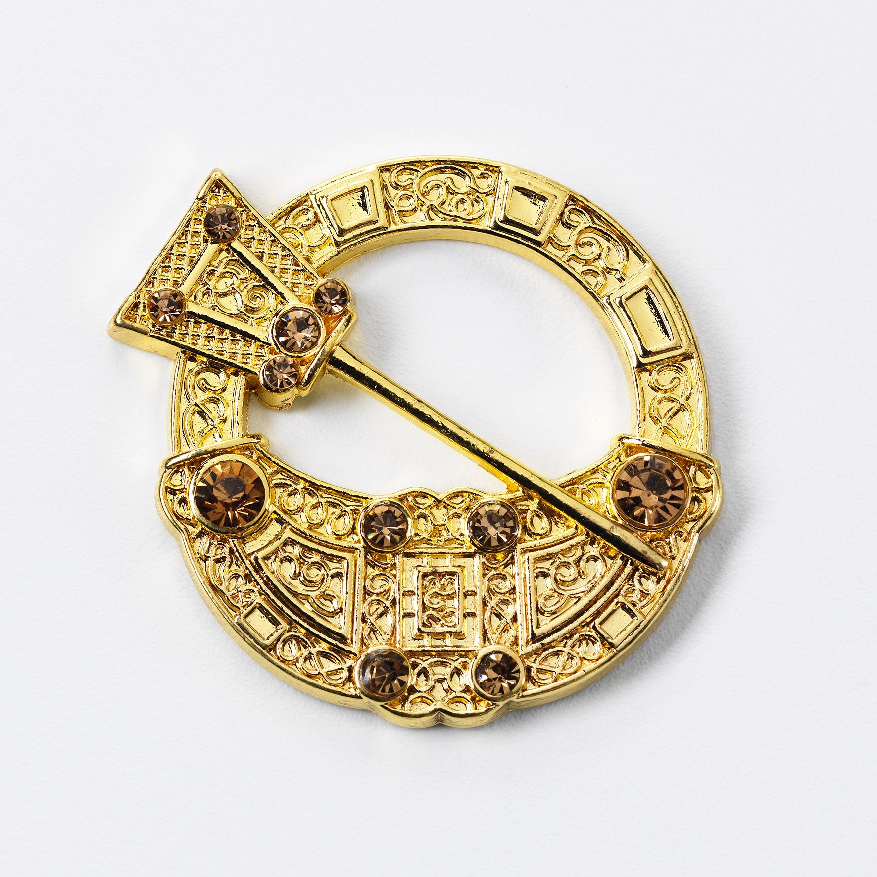 A metal magnet with a gold finish depicting the Hunterston brooch. The brooch's pin sits across an opening in the centre of the round brooch, Norse knot work and beads are features on the surrounding ring.
