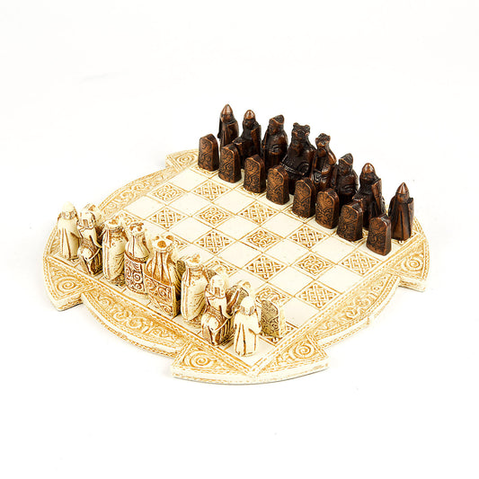 A round cream resin box lid with a chess board incorporated. It is decorated around the edge and on the board squares with knot work patterns. A game is set up on the board of a set of brown and a set of white Lewis chess pieces.