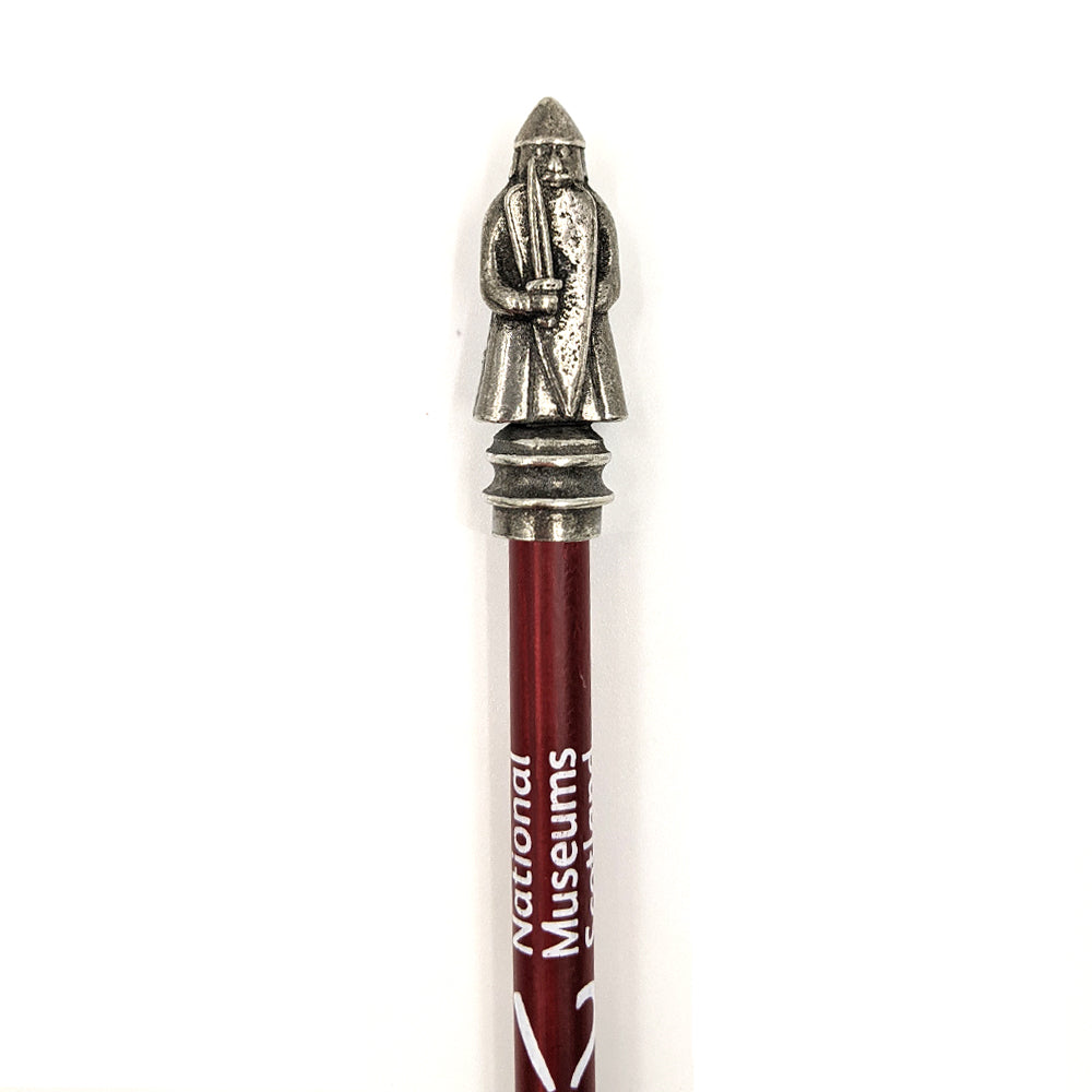 Metal pencil topper of a Lewis chess piece berserker on top of a maroon pencil with the National Museums Scotland logo printed in white.