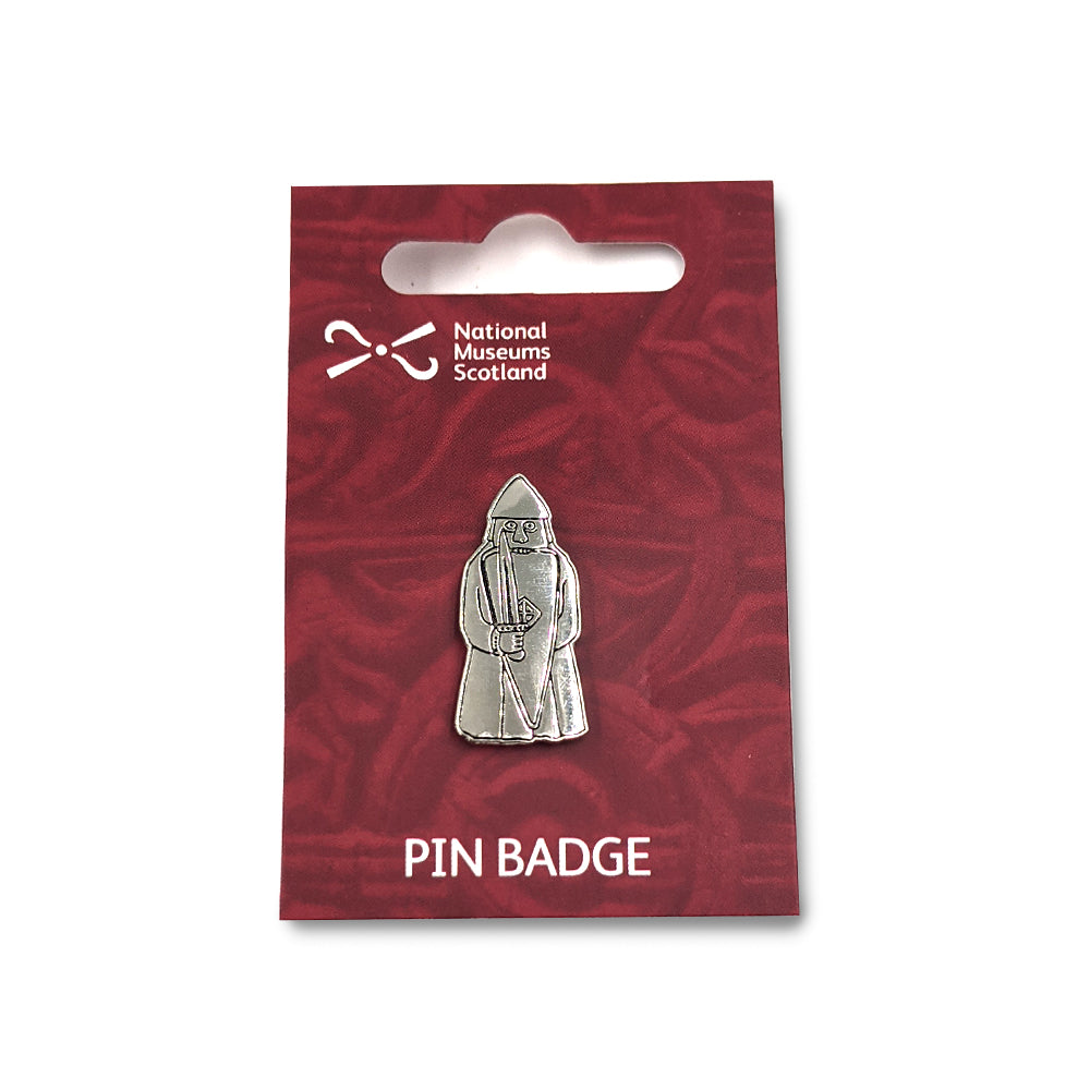 A metal pin badge etched with a line illustration of a berserker Lewis chess piece. The pin badge is on a maroon red backing card  with a faint knot work design, the National Museums Scotland in the top left and the words "Pin Badge" across the bottom edge in white.