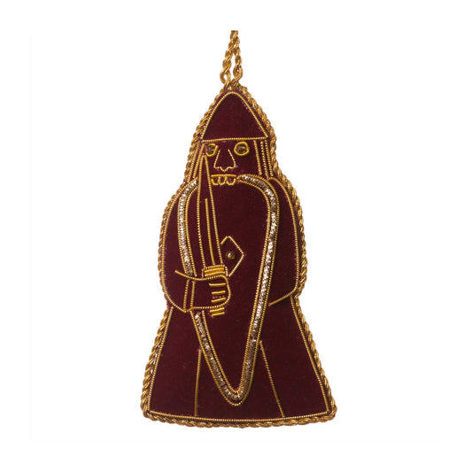An embroidered hanging decoration of a berserker Lewis chess piece. The decoration is made from maroon felt and embroidered with gold thread detailing.