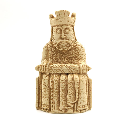 A plastic resin replica magnet of a king Lewis chess piece. The king wearing a crown and long robes sits on a throne holding a sword horizontally across his knee.