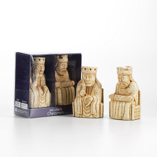 A purple cardboard box with a cellophane window with a resin replica of a queen Lewis chess piece and a king Lewis chess piece. To the right sits both replicas outside of the box.