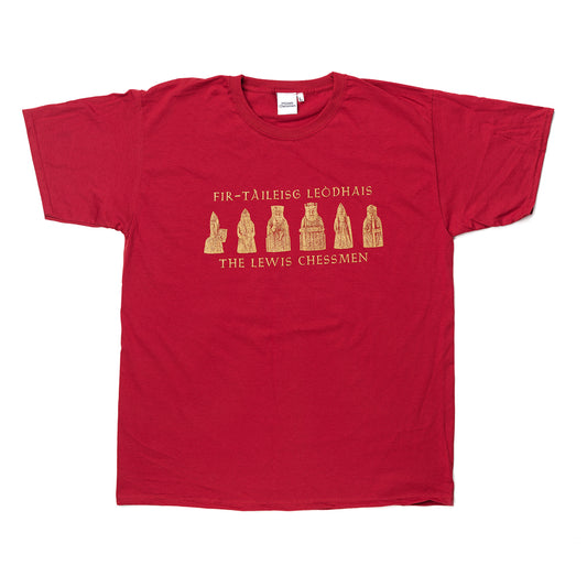 A red cotton short sleeved t-shirt. The t-shirt is printed with illustrations of the six Lewis chess pieces, below the pieces are the words "The Lewis Chessmen" and above are the words translated into Gaelic "Fir- Taileisg Leodhais". The printing is in a metallic bronze.