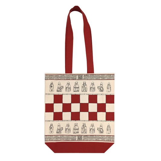 A cream coloured tote bag with a rad base and handle. The centre of the bag features a red chess board design, above and below the chess board are line illustrations of the Lewis chessmen and along the top and bottom edge of the bag are rows of knot work designs.