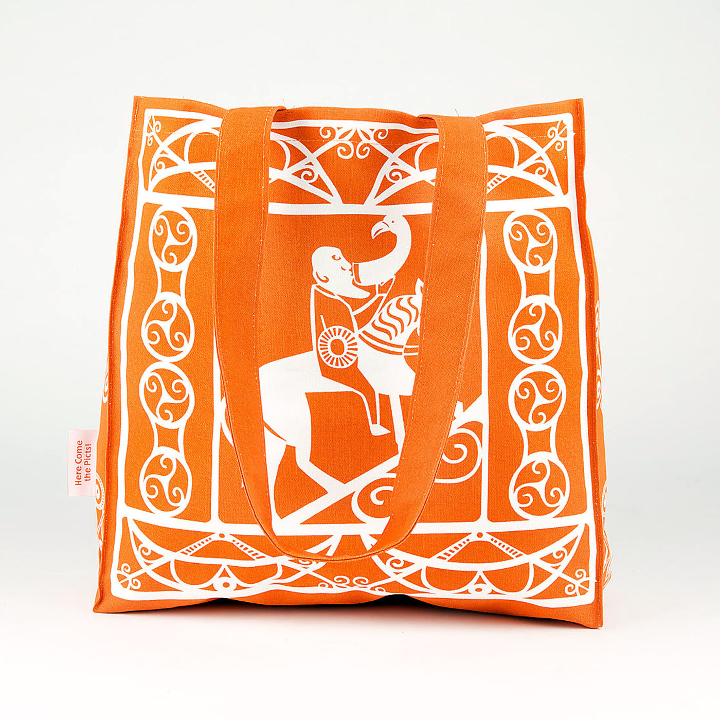 An orange cotton shopper bag with a white printed design taken from Pictish carvings of Pictish pattern work and a man drinking whilst riding a horse.