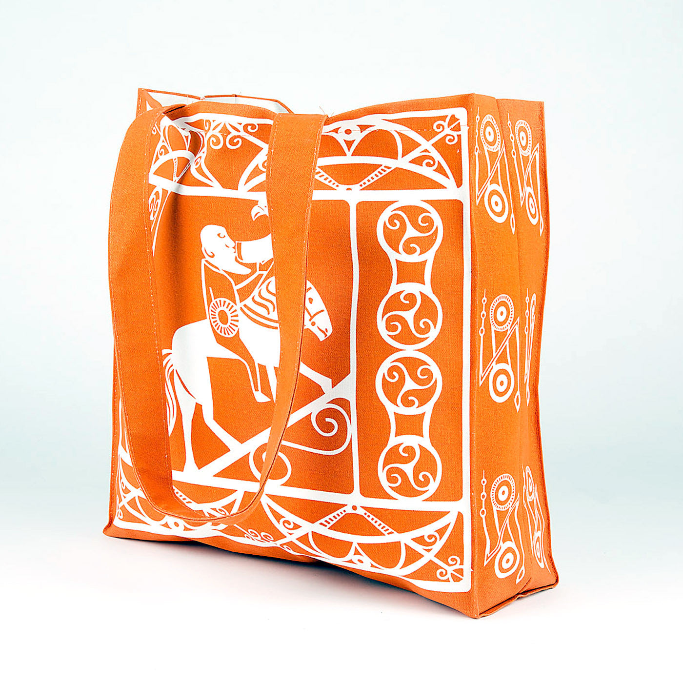 An orange cotton shopper bag with a white printed design taken from Pictish carvings of Pictish pattern work and a man drinking whilst riding a horse.