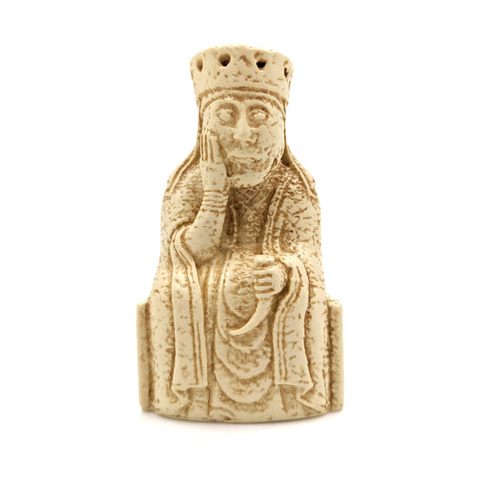 A plastic resin replica magnet of a queen Lewis chess piece. The queen is wearing a crown and long robes and is sitting on a throne with her face in her right hand and a drinking horn in her left.