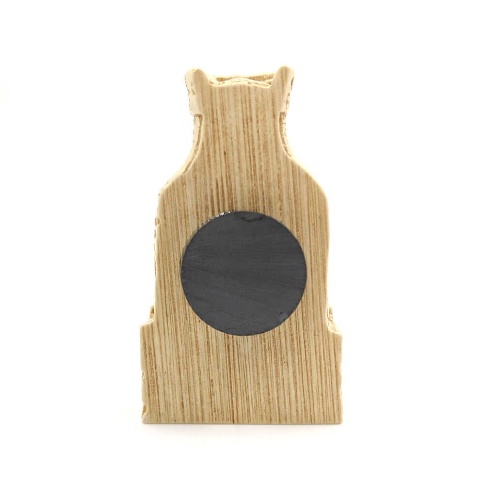 A plastic resin replica magnet of a queen Lewis chess piece. A side view with the king cut in half with a round magnet attached to the back.