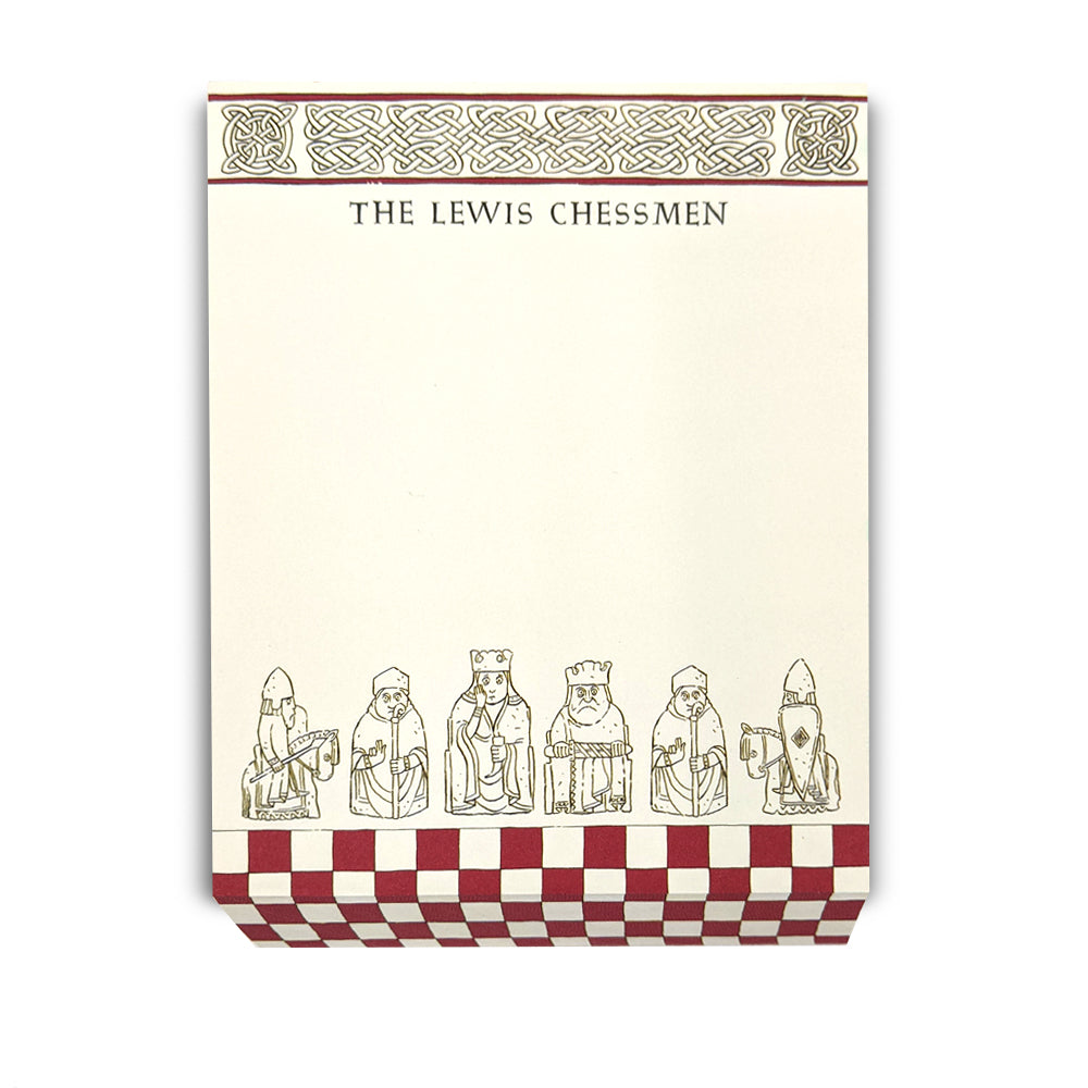 A slanted cream coloured memo pad. The top edge has a row of knot work designs with the words "The Lewis Chessmen" underneath. The bottom edge has a red chess board pattern with a row of illustrations of assorted Lewis chess pieces.