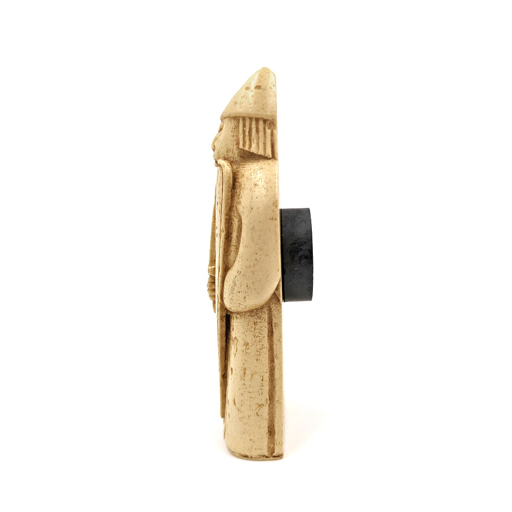 A plastic resin replica magnet of a berserker Lewis chess piece. A warrior holding a sword in front of a long shield wearing a long tunic and pointed helmet, he is biting down onto the top edge of his shield. A side view with the berserker cut in half with a round magnet attached to the back.