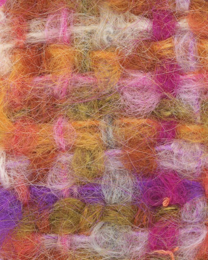 A close up photograph of some of Bernat Klein's fabric. The fabric is woven in pink, white and orange.