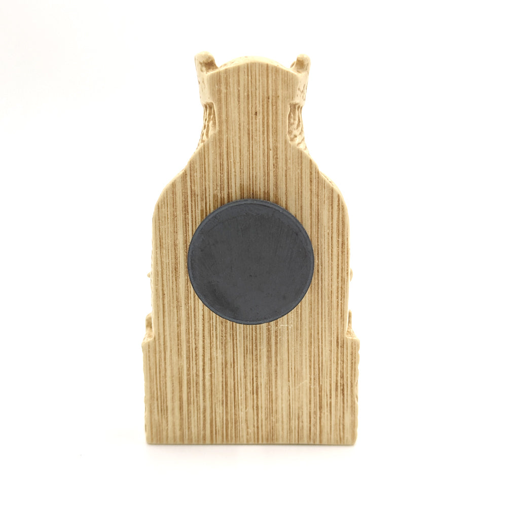 A plastic resin replica magnet of a king Lewis chess piece. A side view with the king cut in half with a round magnet attached to the back.