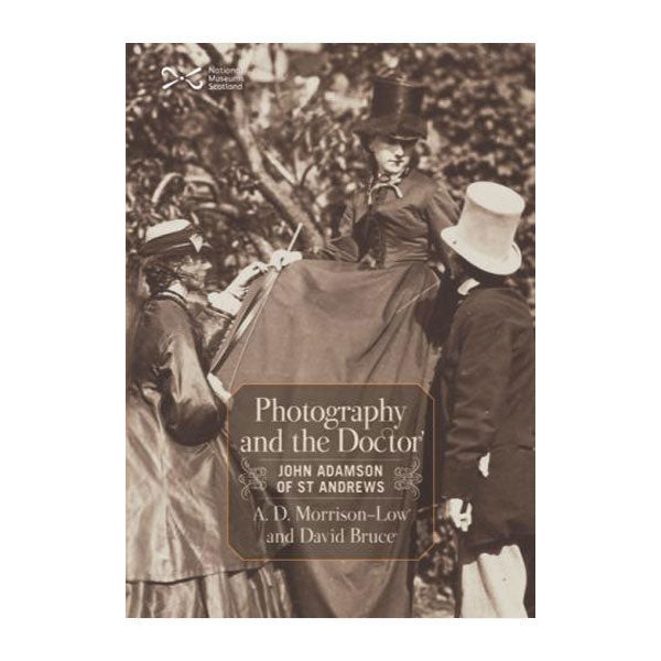 Book cover with a black and white photograph of two women and a man in Victorian clothing in a garden. A woman is sitting on a tree branch wearing a long dress and top hat, she is looking down to the right at a man in a tailcoat and a white top hat, on the left a woman in a dress and veil is leaning onto her knee and looking up at her.